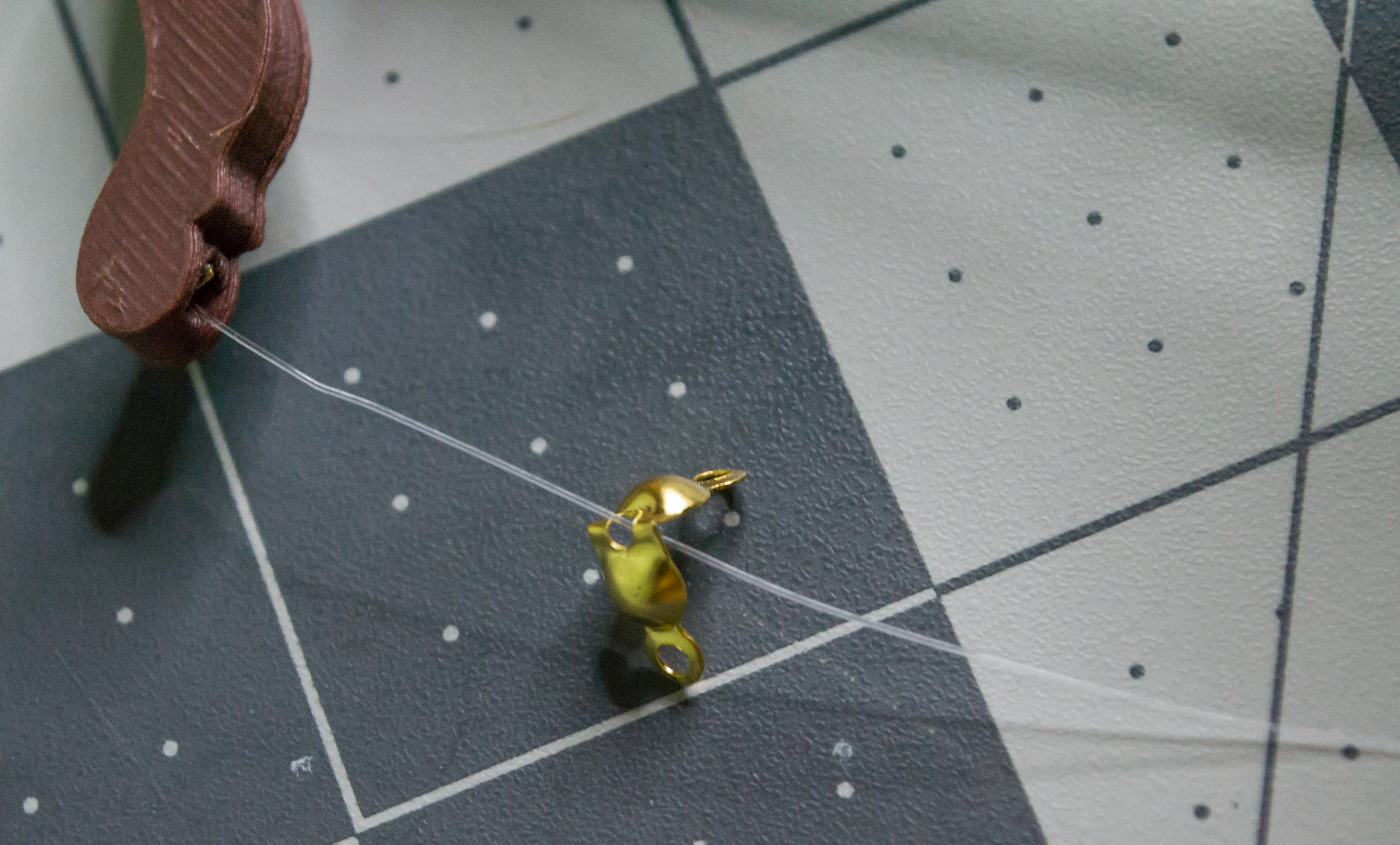 Gold clamshell bead put onto the monofilament line coming from the lever component on VintageScale.