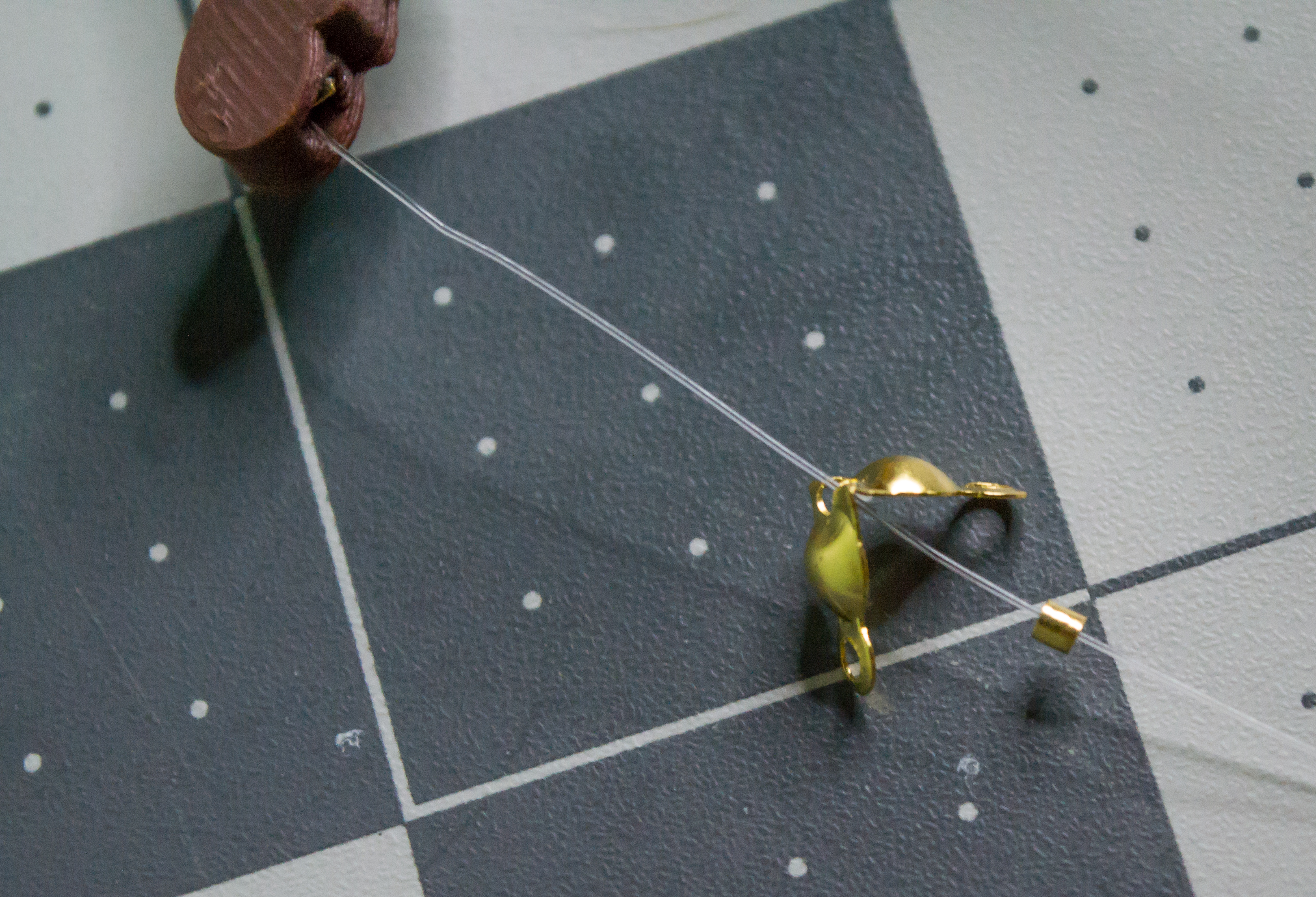 Added a small gold crimp bead to the lever component monofilament line after the gold clamshell bead.