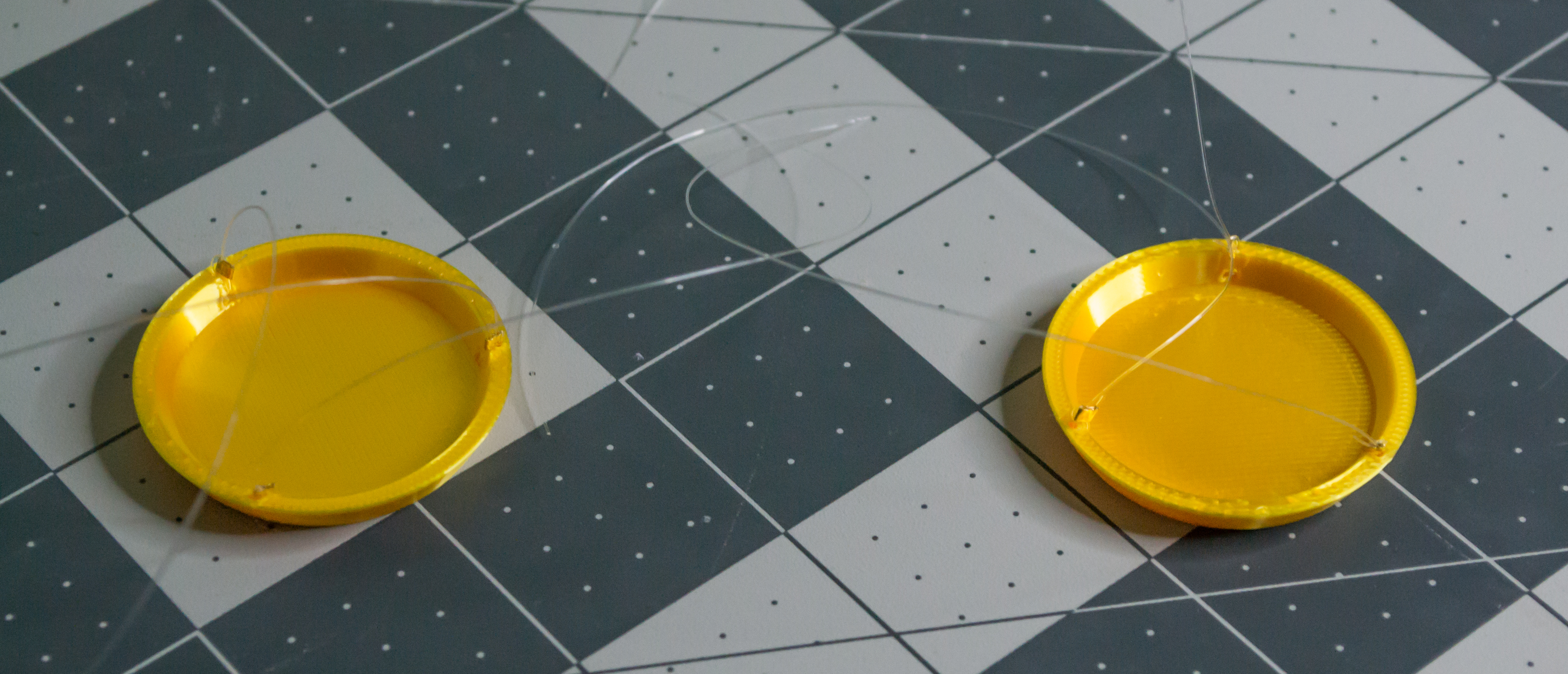 Both 3D printed gold plates completed, each with three monofilament lines attached by crimping small gold beads.